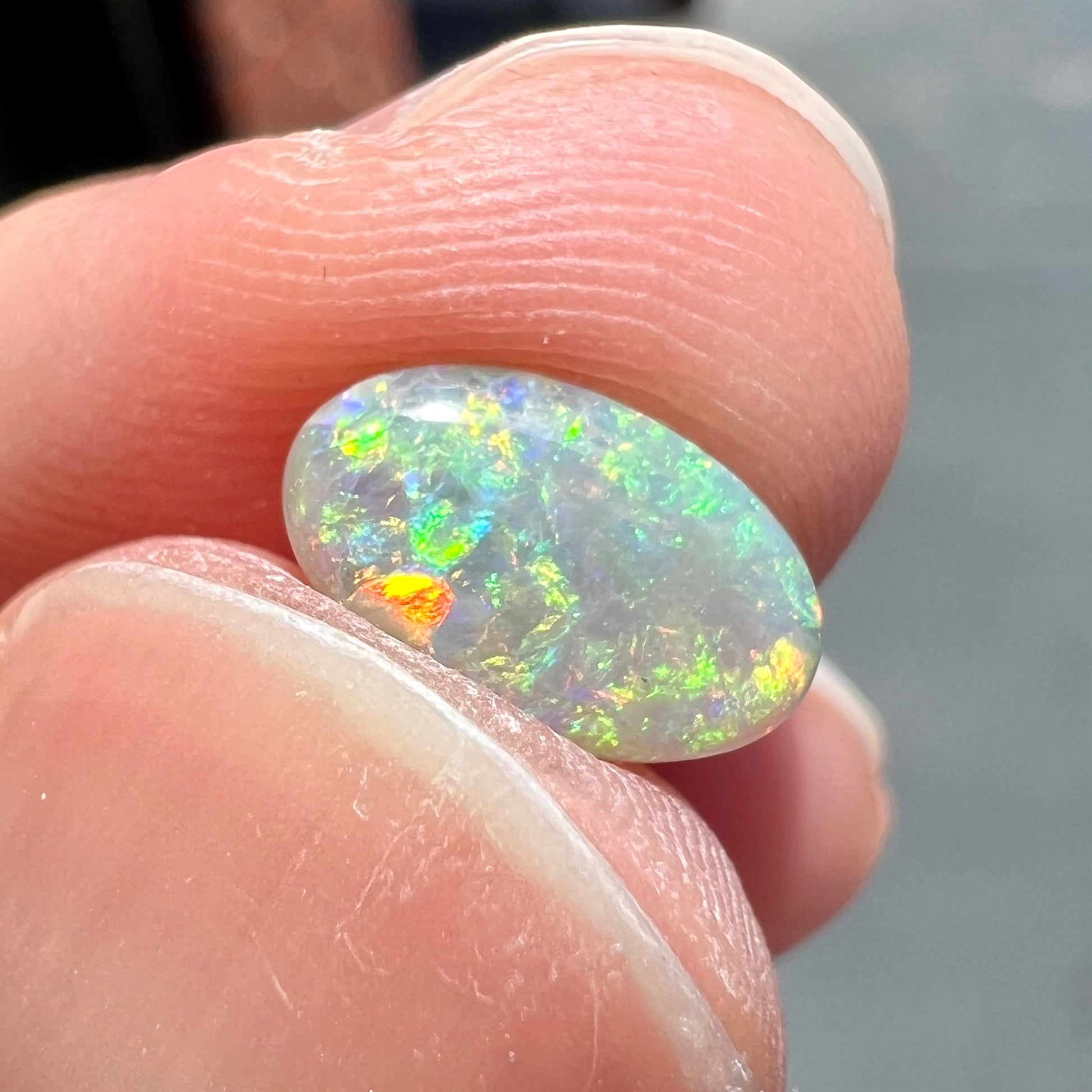 A loose, oval cabochon cut semi-black opal stone from Lightning Ridge, Australia.