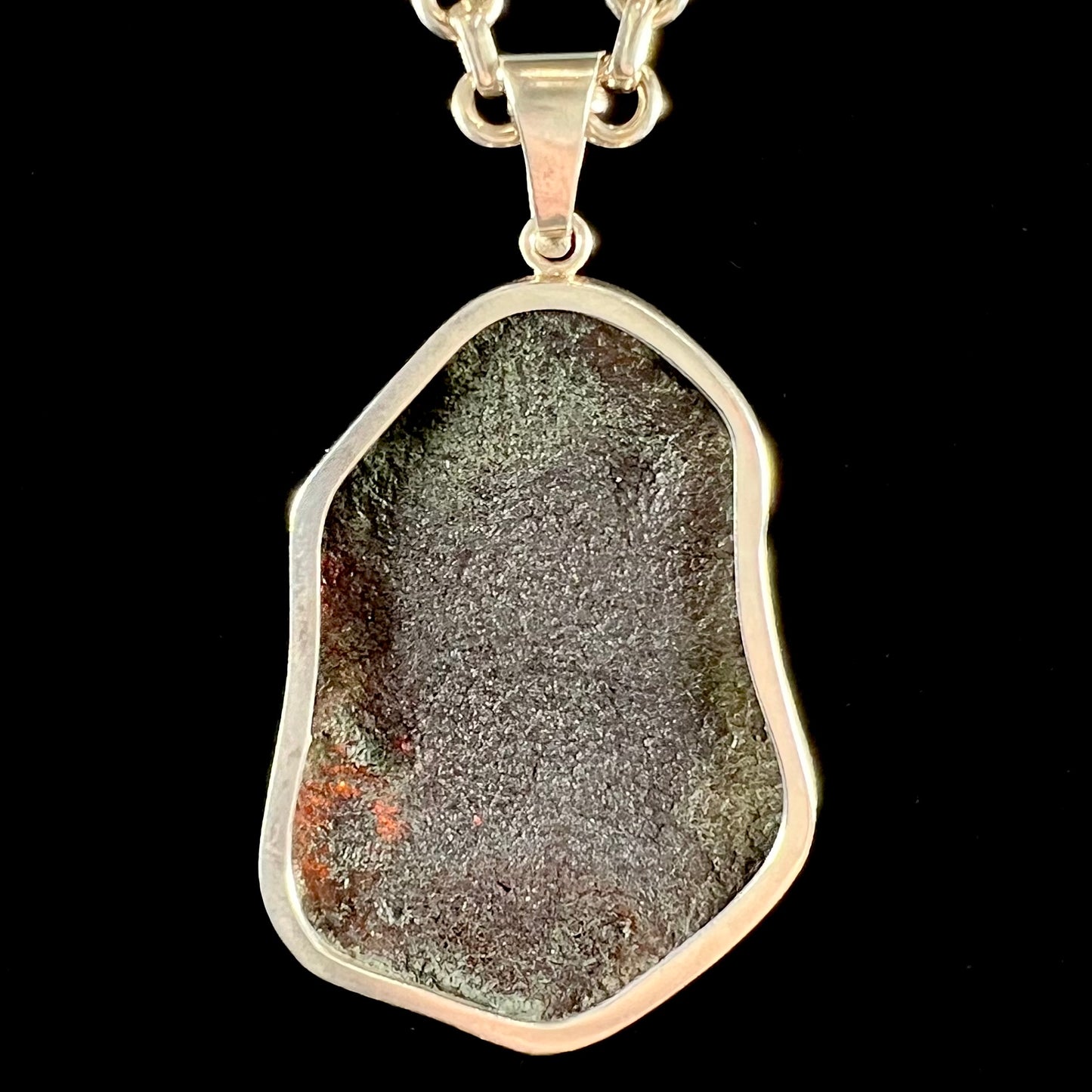 A sterling silver pendant set with a large natural amber stone.  The amber has sun spangled inclusions.