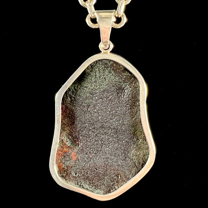 A sterling silver pendant set with a large natural amber stone.  The amber has sun spangled inclusions.