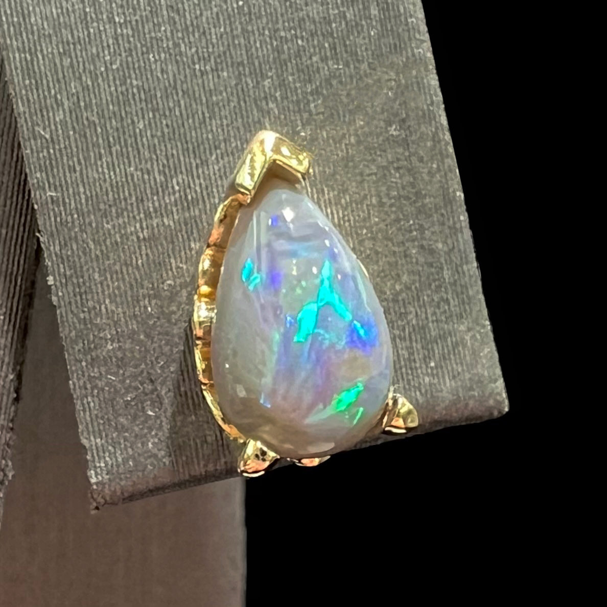 A pair of pear shaped natural black opal stud earrings in filigree style yellow gold baskets.