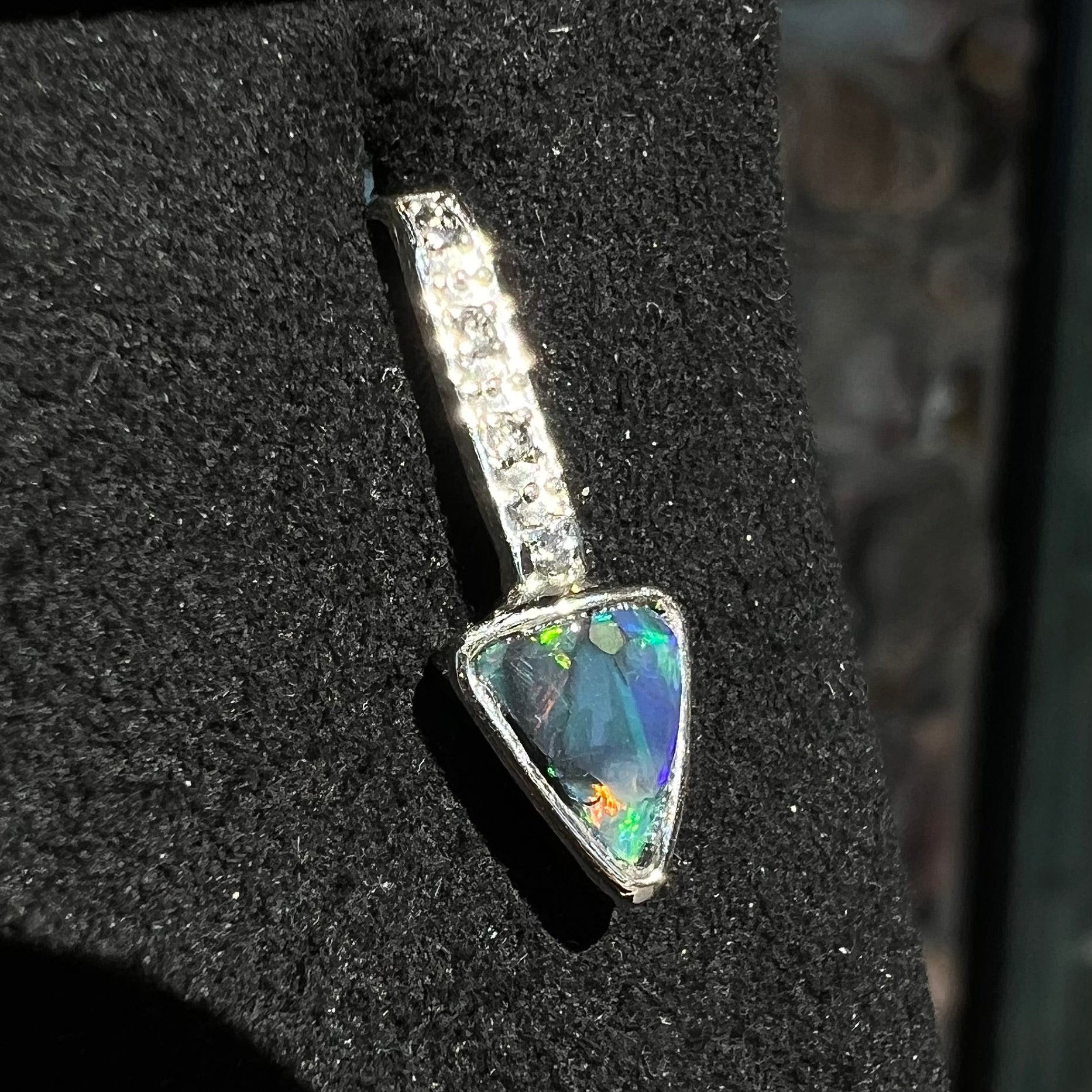 A white gold pendant and earrings set mounted with triangle cut natural black opals and diamonds.