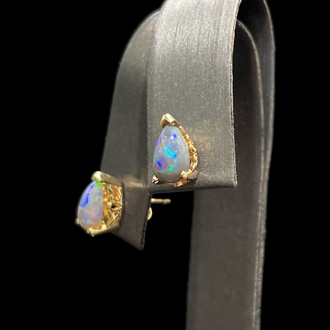 A pair of pear shaped natural black opal stud earrings in filigree style yellow gold baskets.