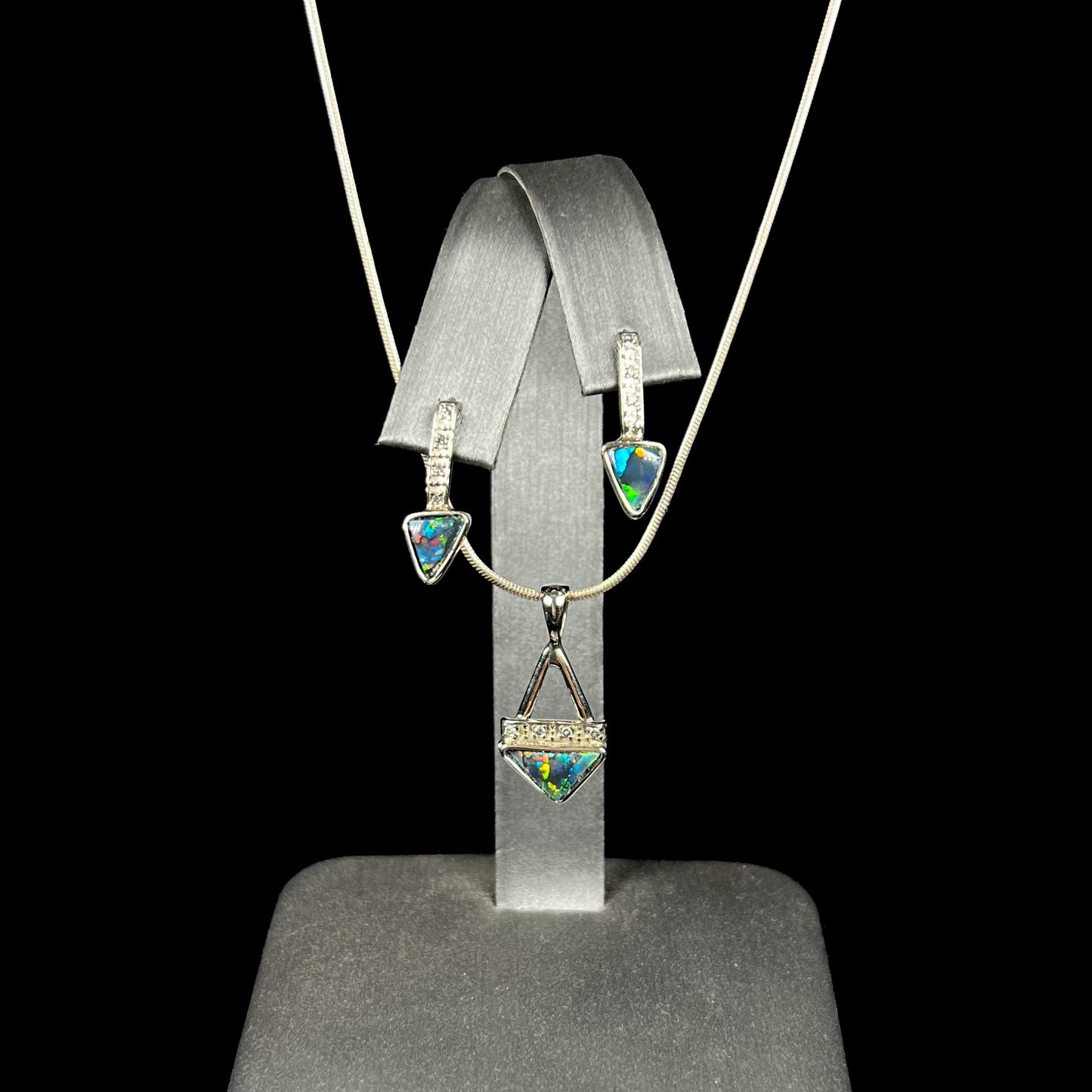 A white gold pendant and earrings set mounted with triangle cut natural black opals and diamonds.