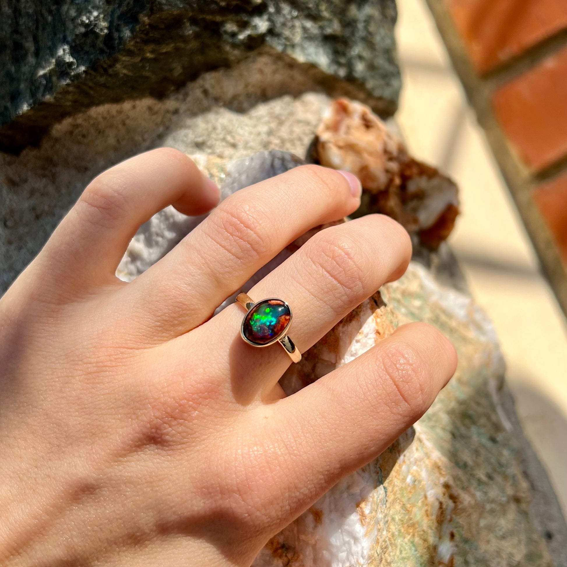 A ladies' yellow gold solitaire ring bezel set with an oval cabochon cut natural black Mexican cantera fire opal stone.
