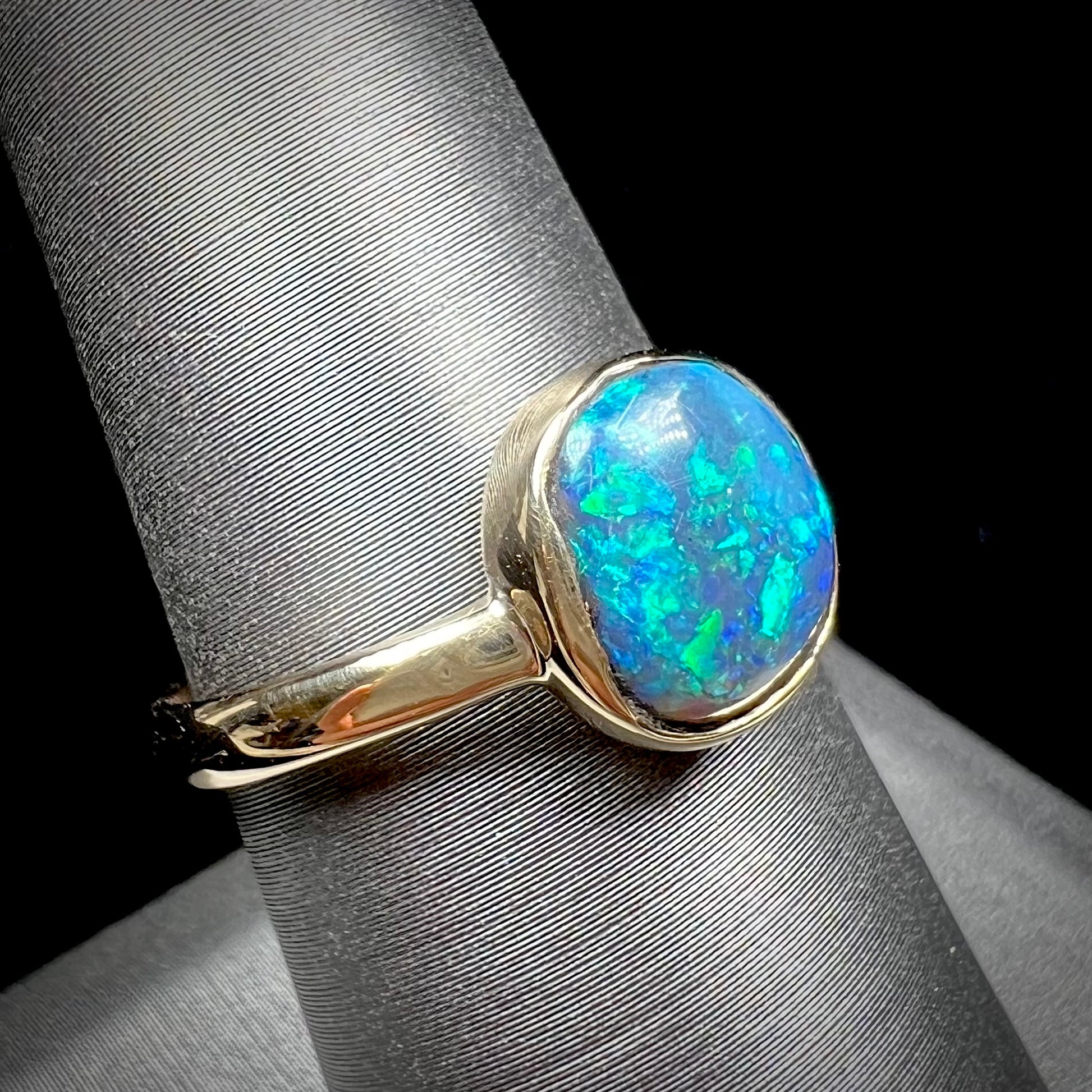 A ladies' natural black crystal opal solitaire ring handmade in 14 karat yellow gold.