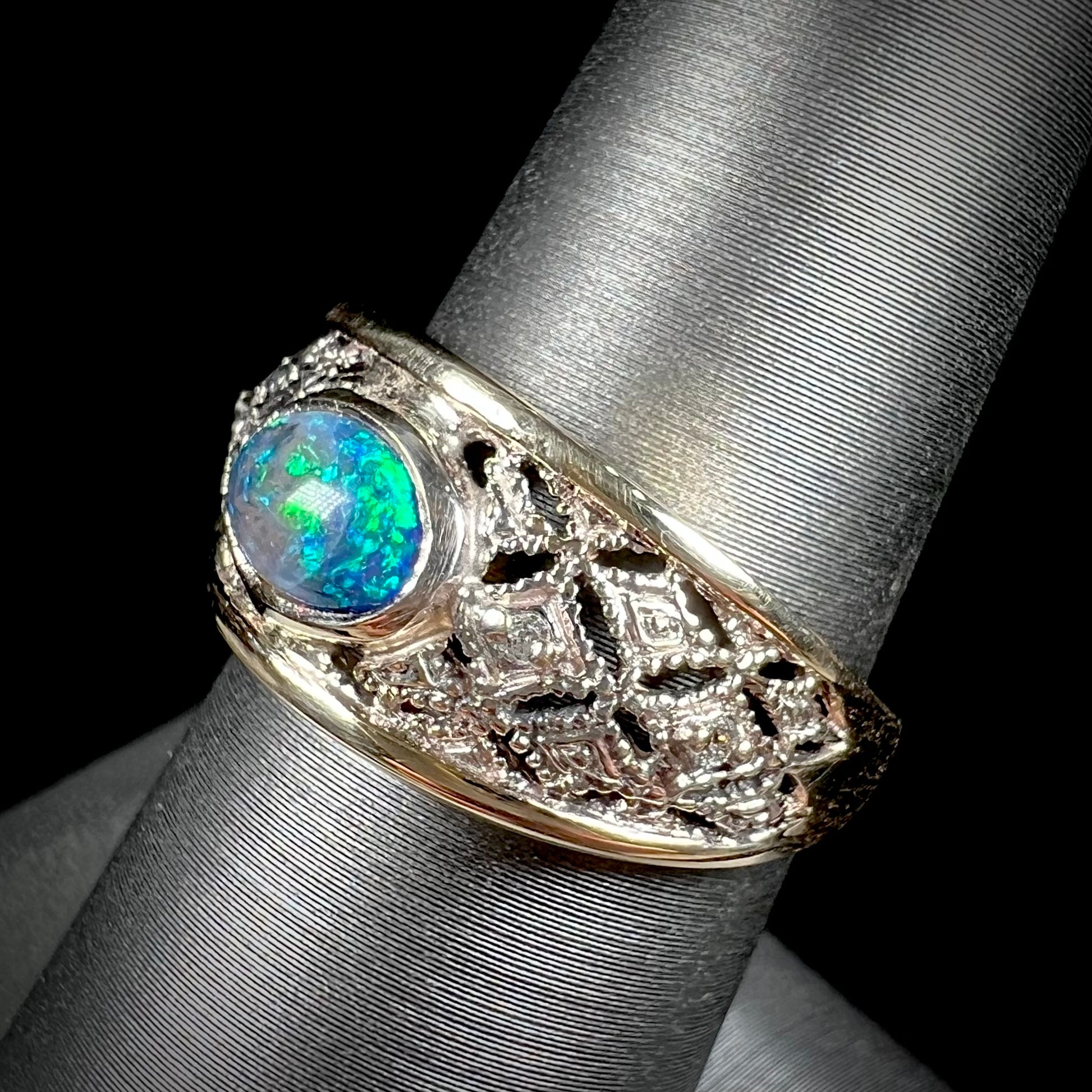 A ladies' yellow gold filigree style ring set with a natural black opal and diamond accents.