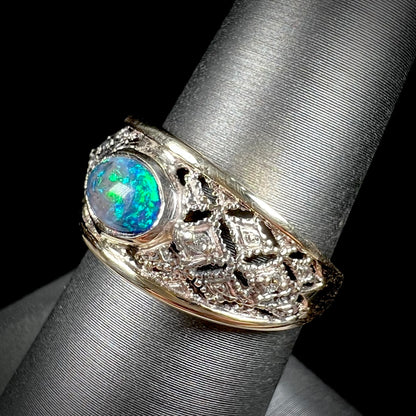 A ladies' yellow gold filigree style ring set with a natural black opal and diamond accents.