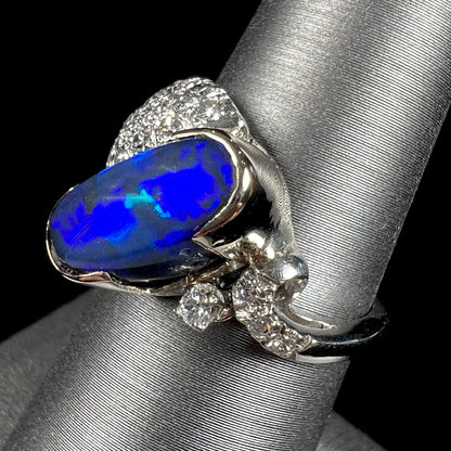 A platinum ring set with an oval cut black opal and round cut diamonds in a leaf design.