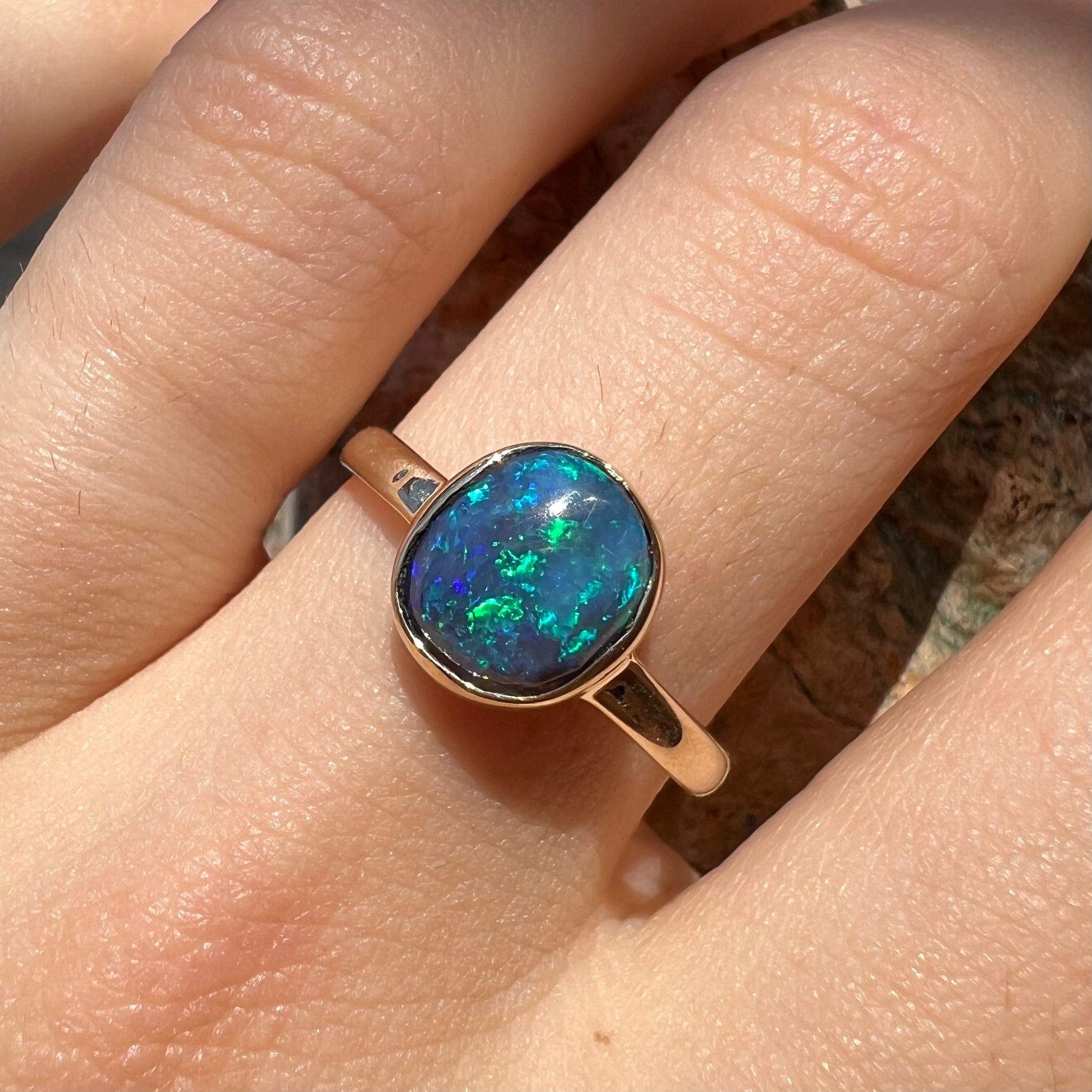 A ladies' natural black crystal opal solitaire ring handmade in 14 karat yellow gold.