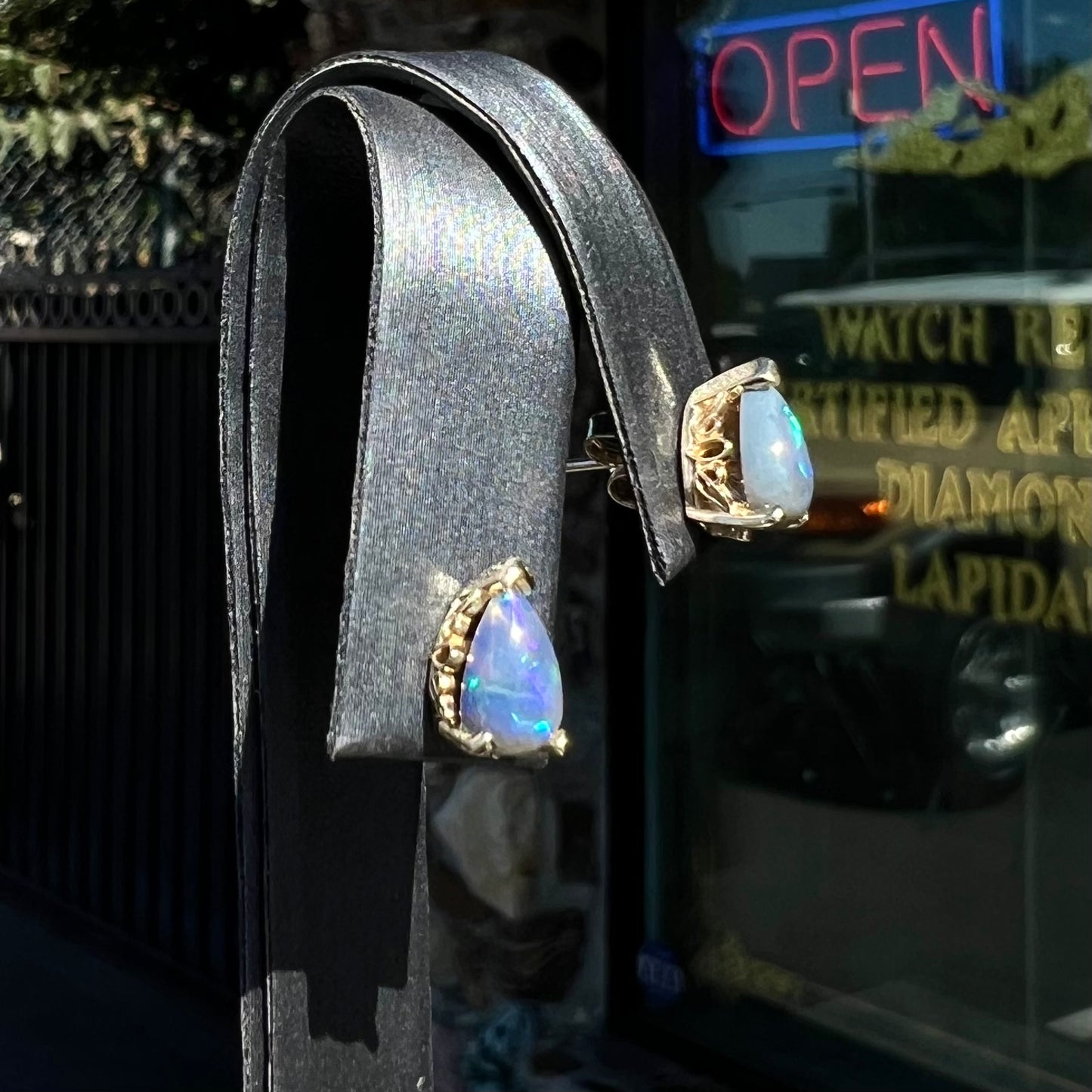 A pair of pear shaped natural black opal stud earrings in filigree style yellow gold baskets.