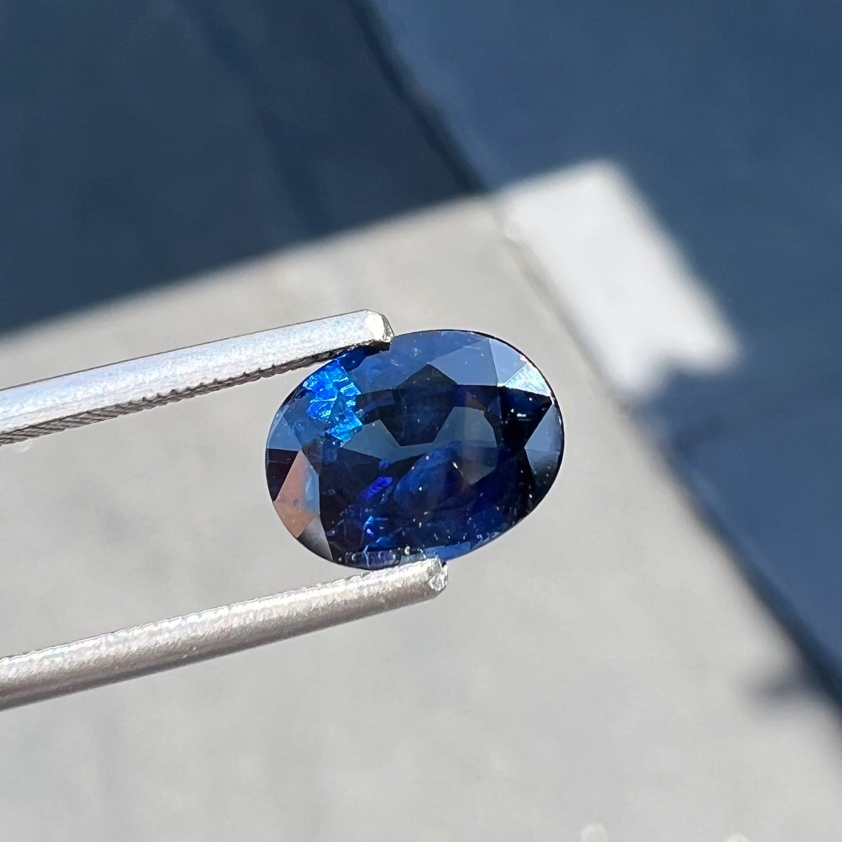 A loose, faceted oval cut natural blue sapphire gemstone.