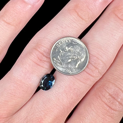 A loose, faceted oval cut natural blue sapphire gemstone.