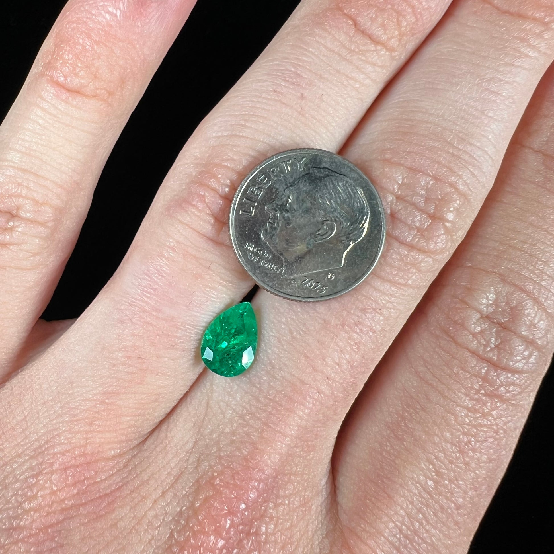A loose, pear shaped natural emerald gemstone.