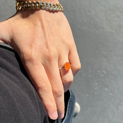 A silver solitaire ring set with a natural, faceted oval cut Mexican fire opal.  The stone is a bright orange color.