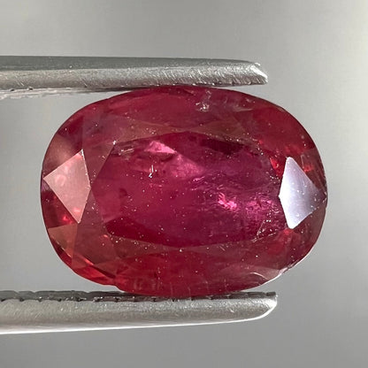 A loose, natural purplish ruby gemstone.  There is a small, minute chip on the girdle of the gem.