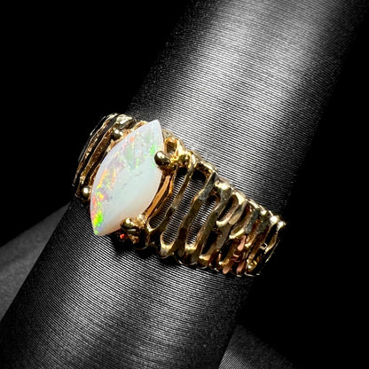 A ladies' yellow gold diamond-cut ring prong set with a natural, marquise cut white opal stone.