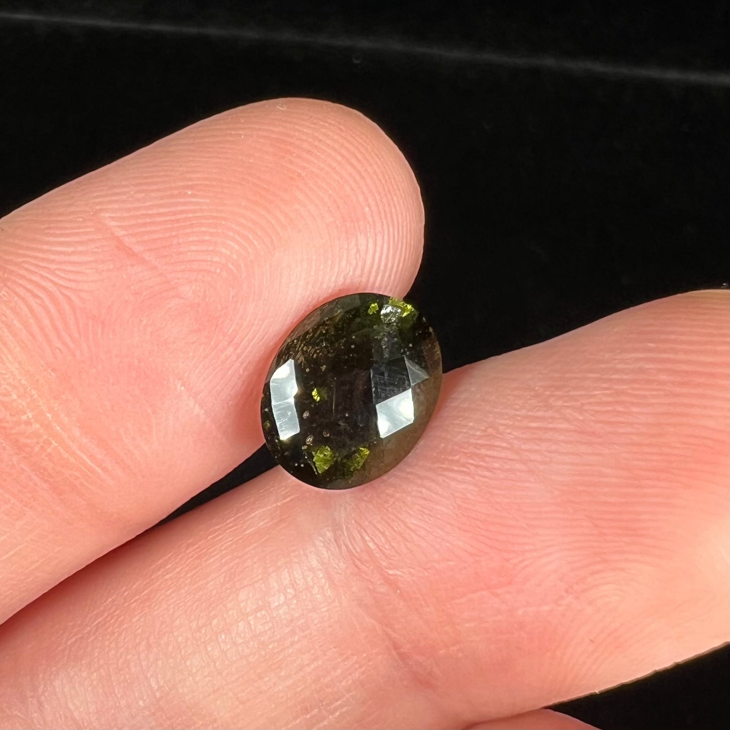 A loose, faceted oval checkerboard moldavite gemstone from the Czech Republic.