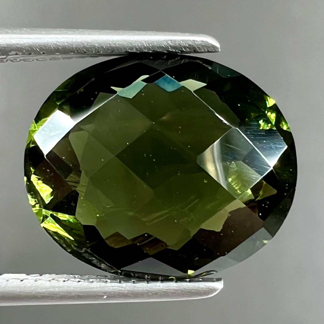 A loose, oval cut natural moldavite gemstone.  The stone weighs 3.85 carats.