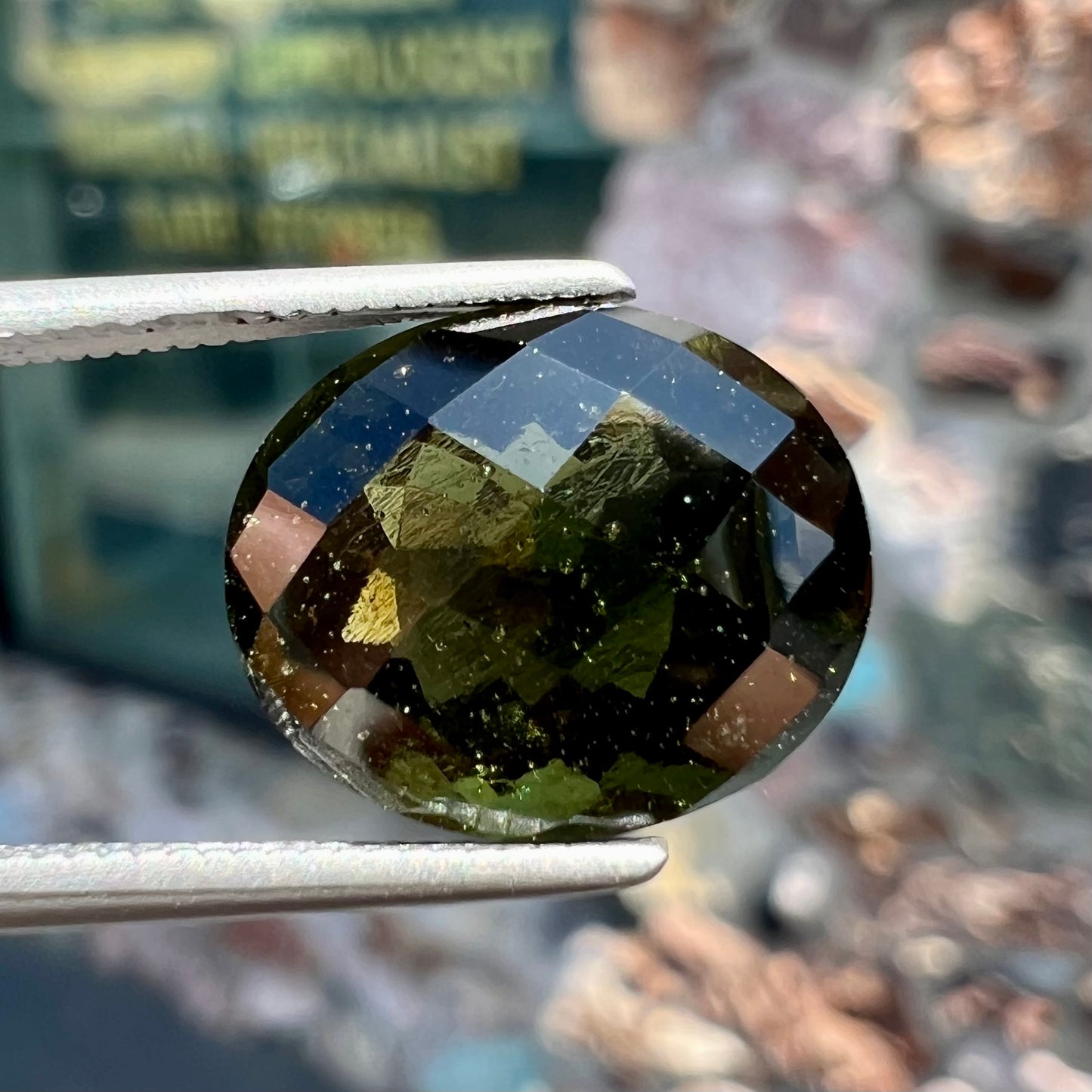 A loose, faceted oval cut natural moldavite gemstone.