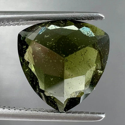 A trillion cut natural moldavite gemstone.  The stone shows inclusions.