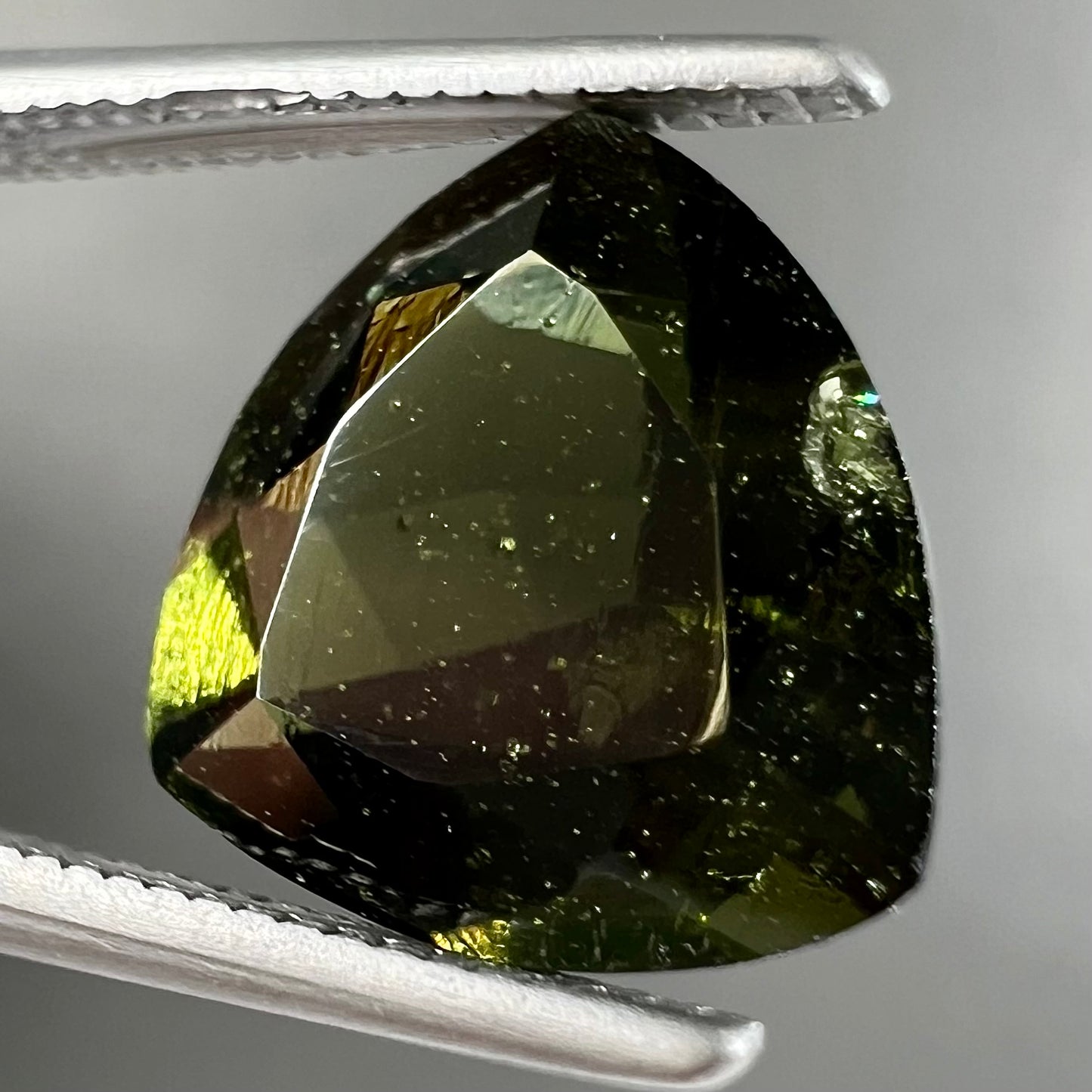 A natural, trillion cut moldavite gemstone.