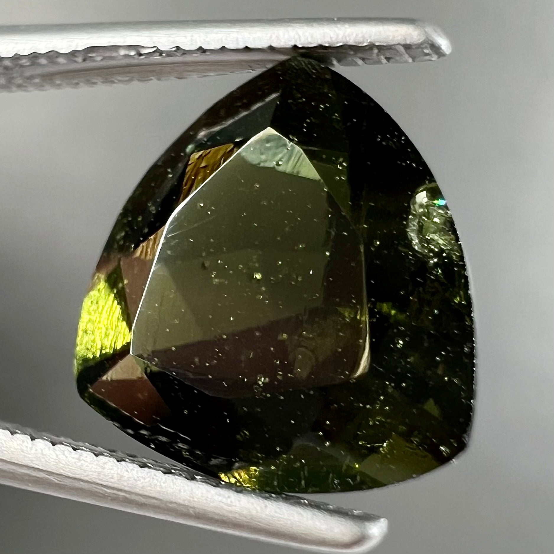 A natural, trillion cut moldavite gemstone.