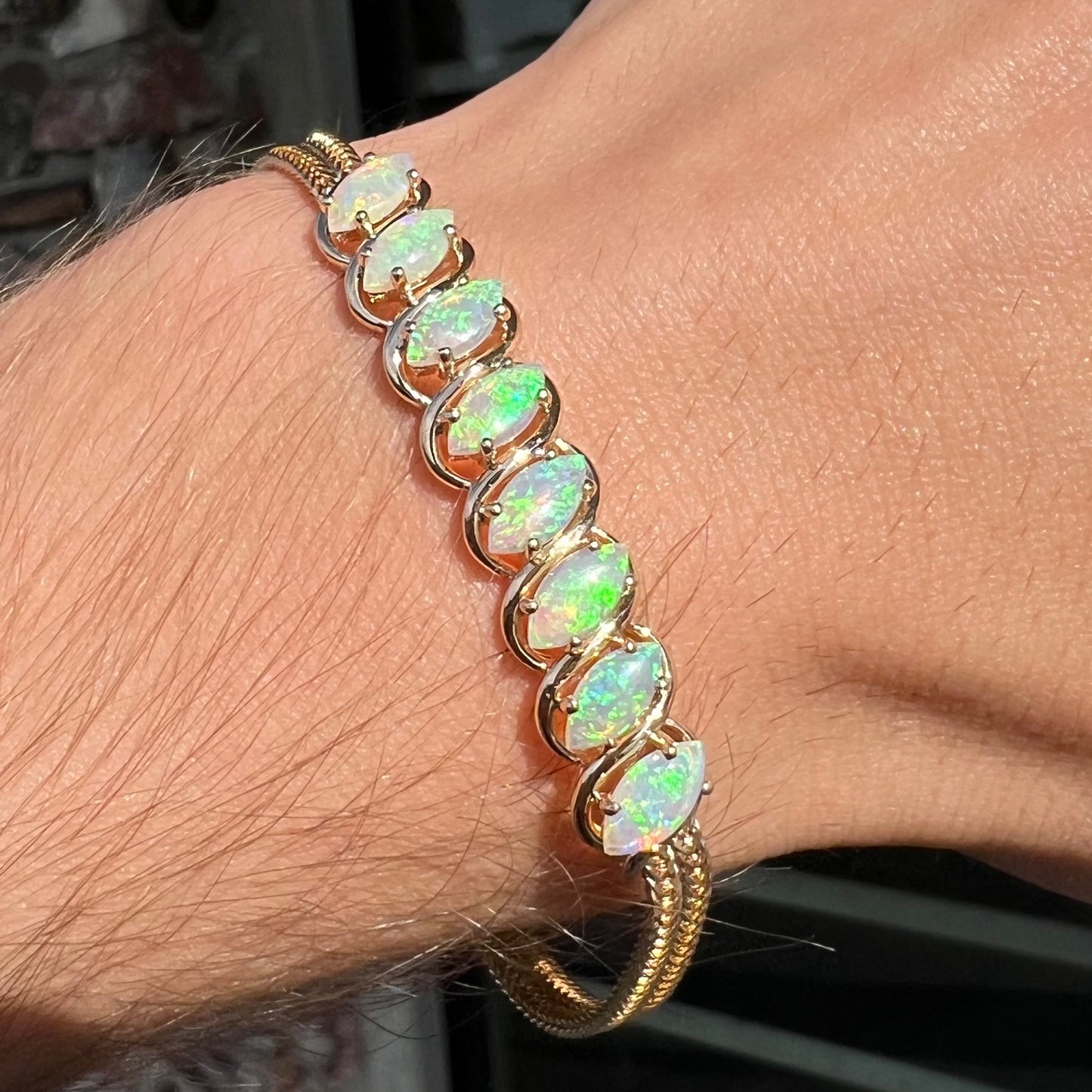 A ladies' yellow gold bracelet prong set with eight natural, marquise cabochon cut opals.