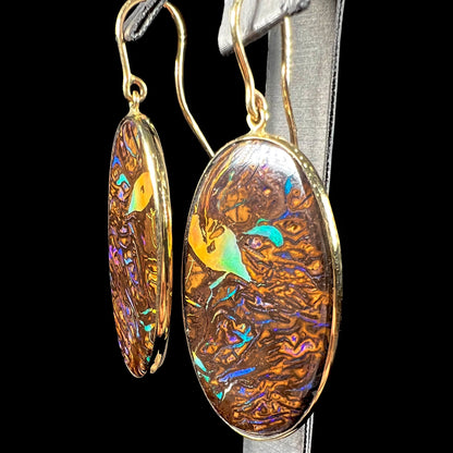 A pair of Koroit boulder opal dangle earrings set in yellow gold bezels.