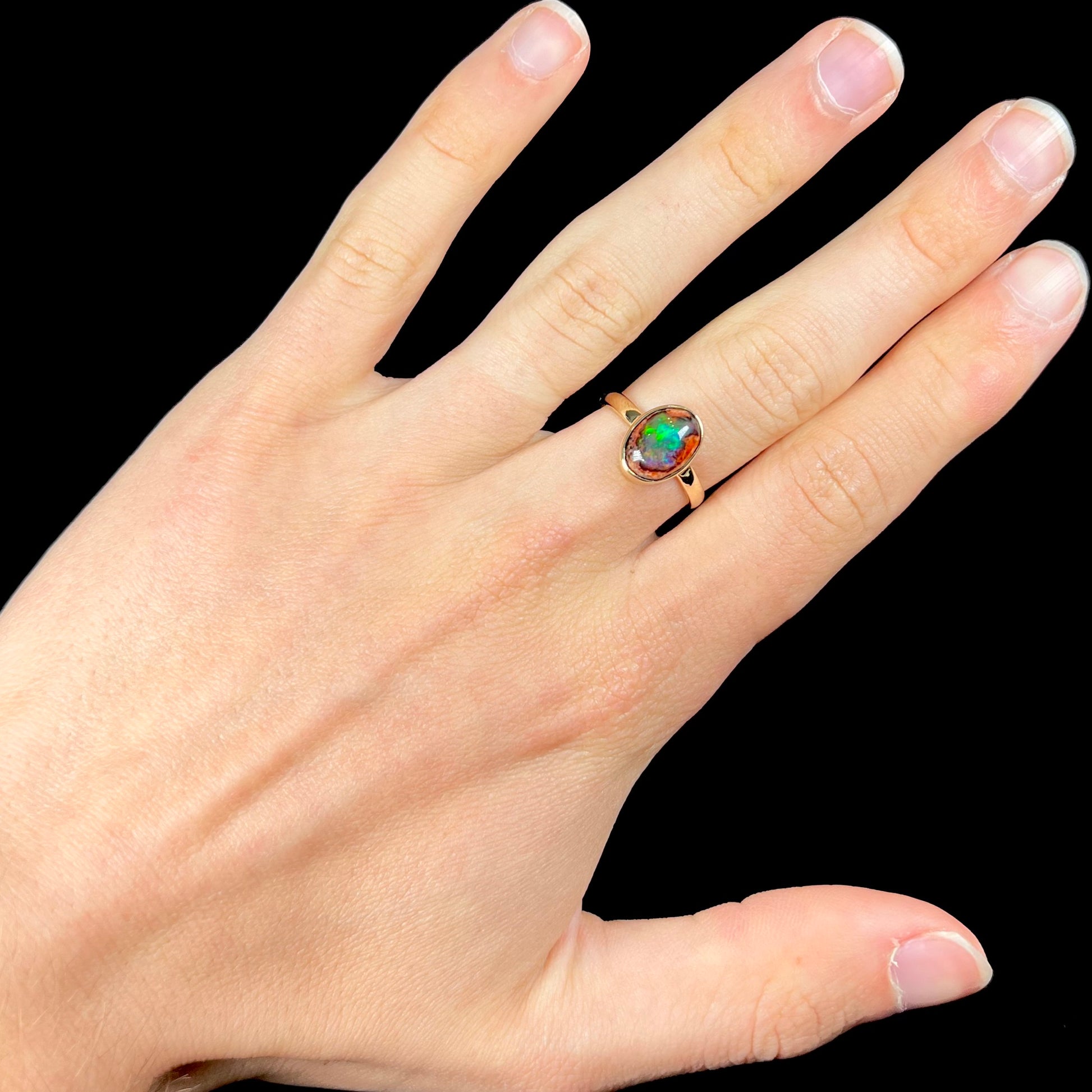 A ladies' yellow gold solitaire ring bezel set with an oval cabochon cut natural black Mexican cantera fire opal stone.