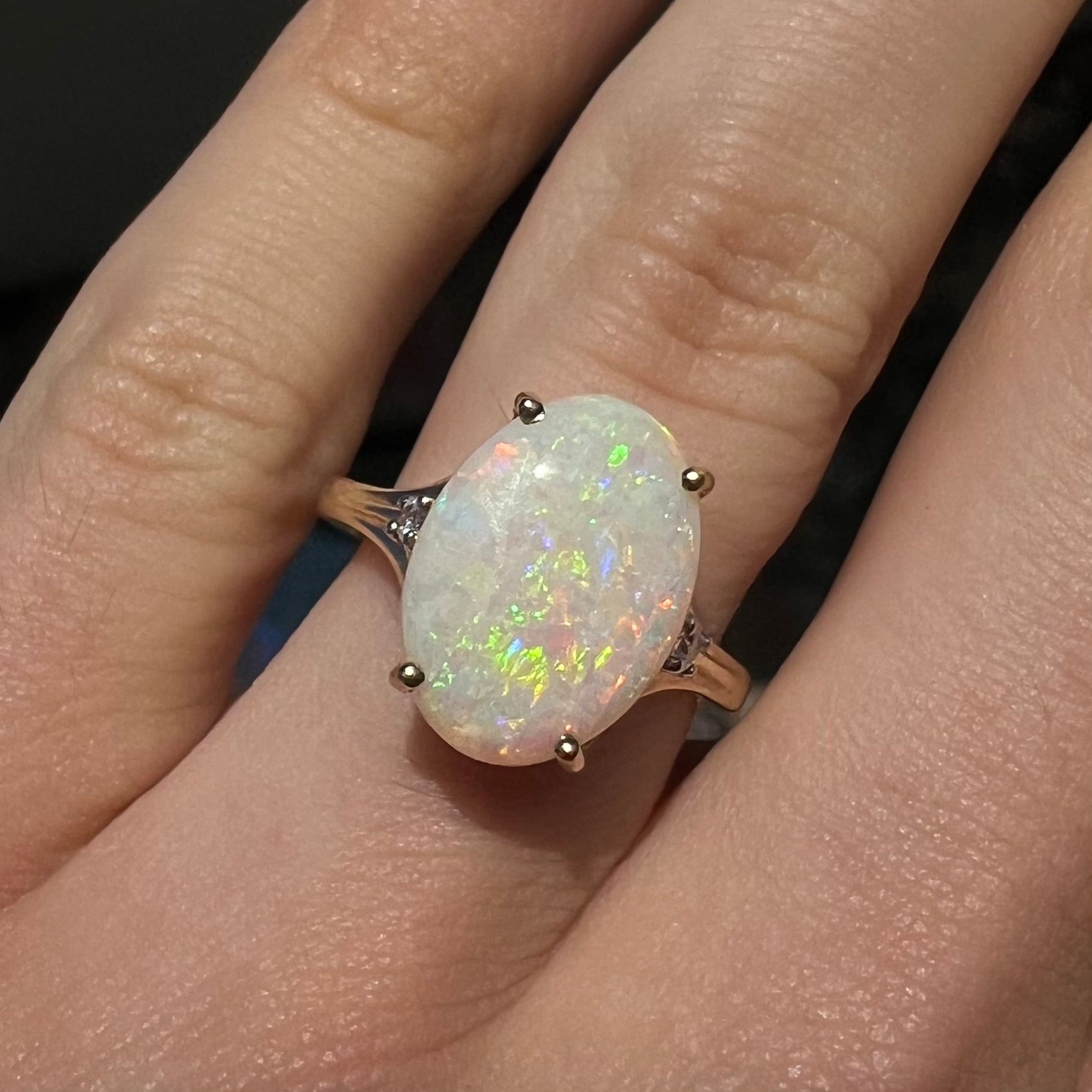 A ladies' yellow gold ring set with two diamonds and an oval cut natural opal stone.