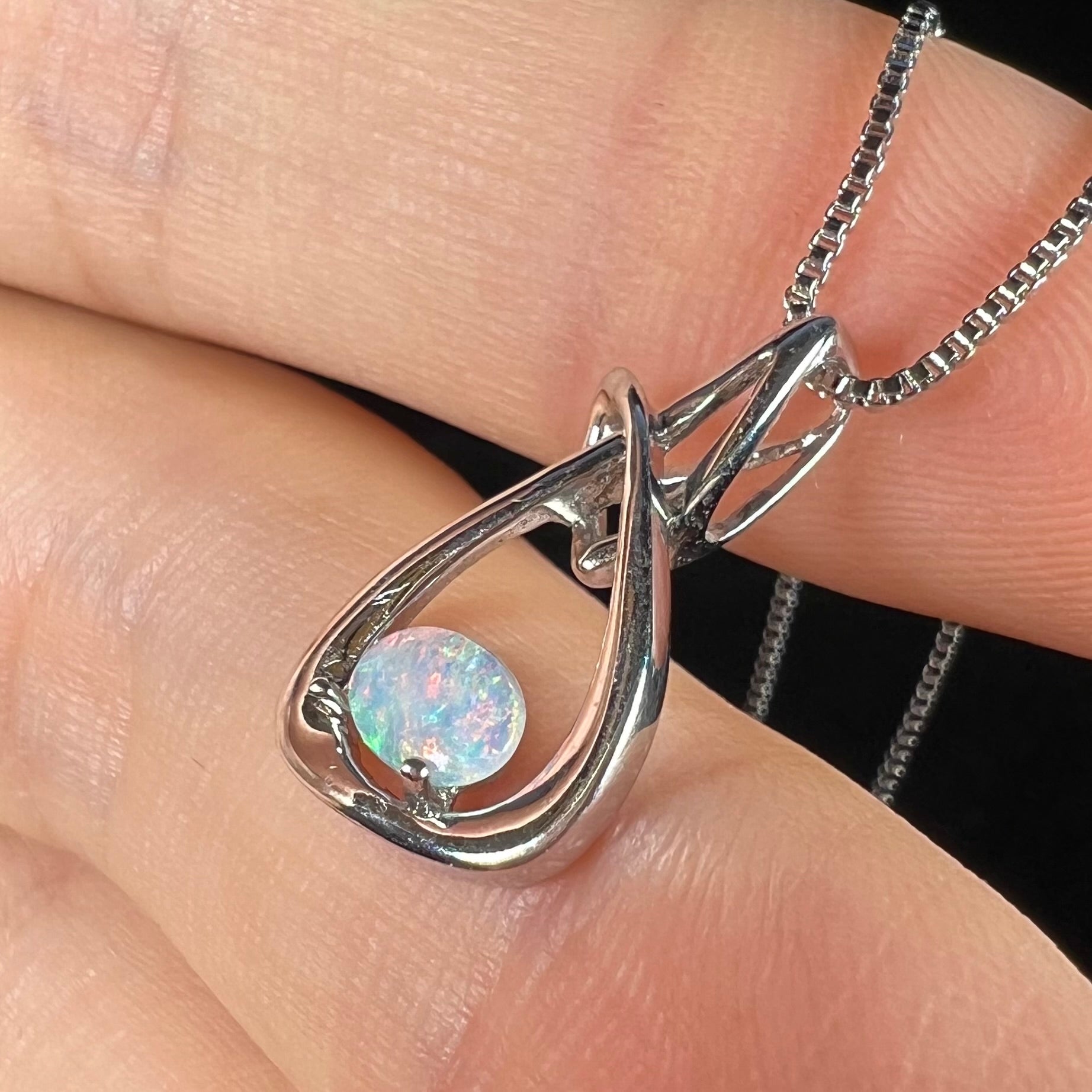 A ladies' sterling silver pendant set with an oval cabochon cut natural white crystal opal.