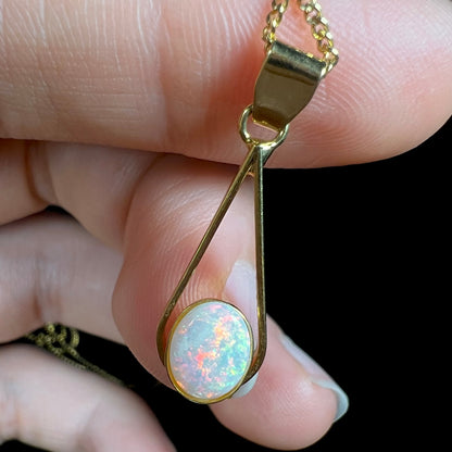 An oval cabochon cut natural white crystal opal set into a gold plated necklace.