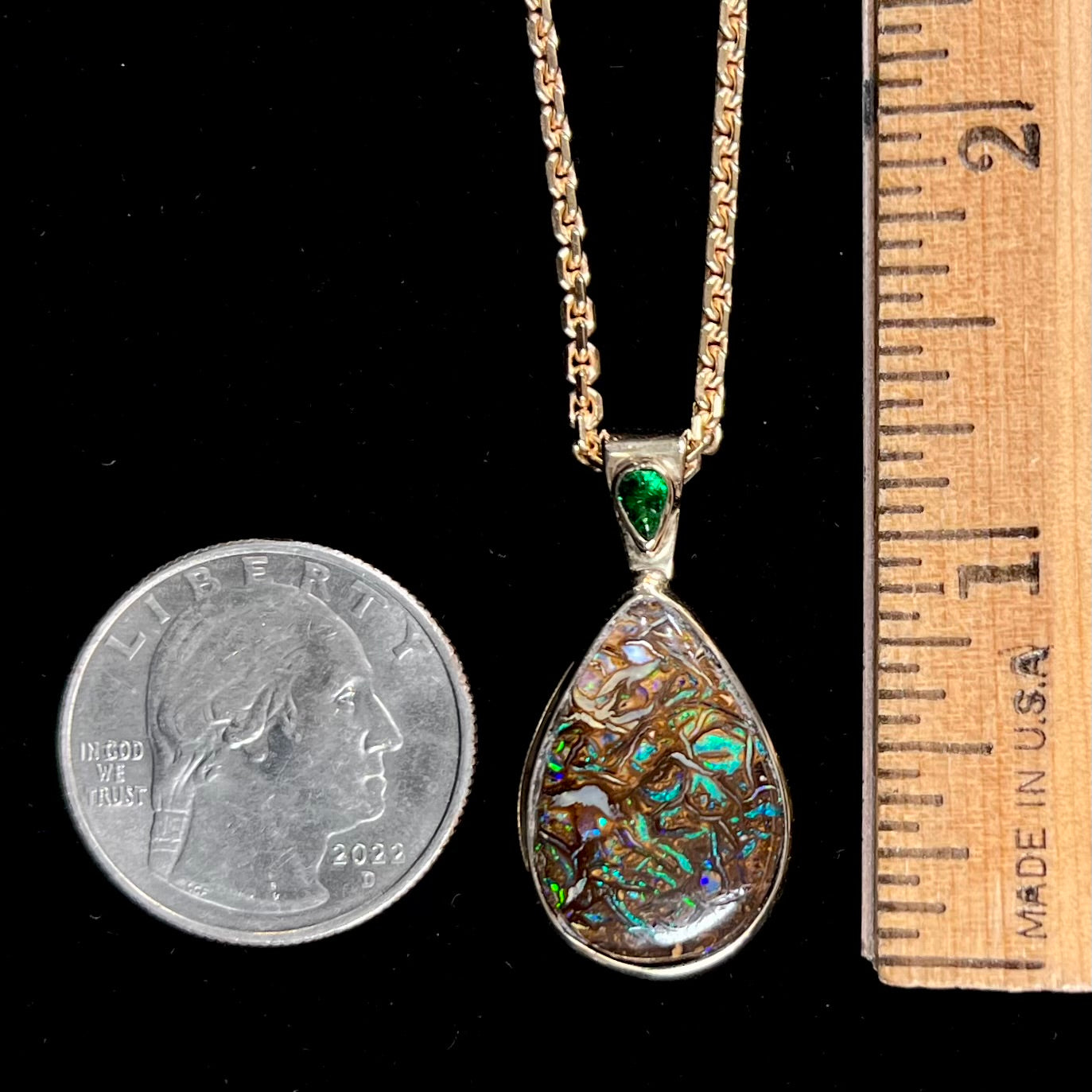 A ladies' yellow gold pendant set with a natural Koroit, Australian boulder opal and a tsavorite garnet accent stone.