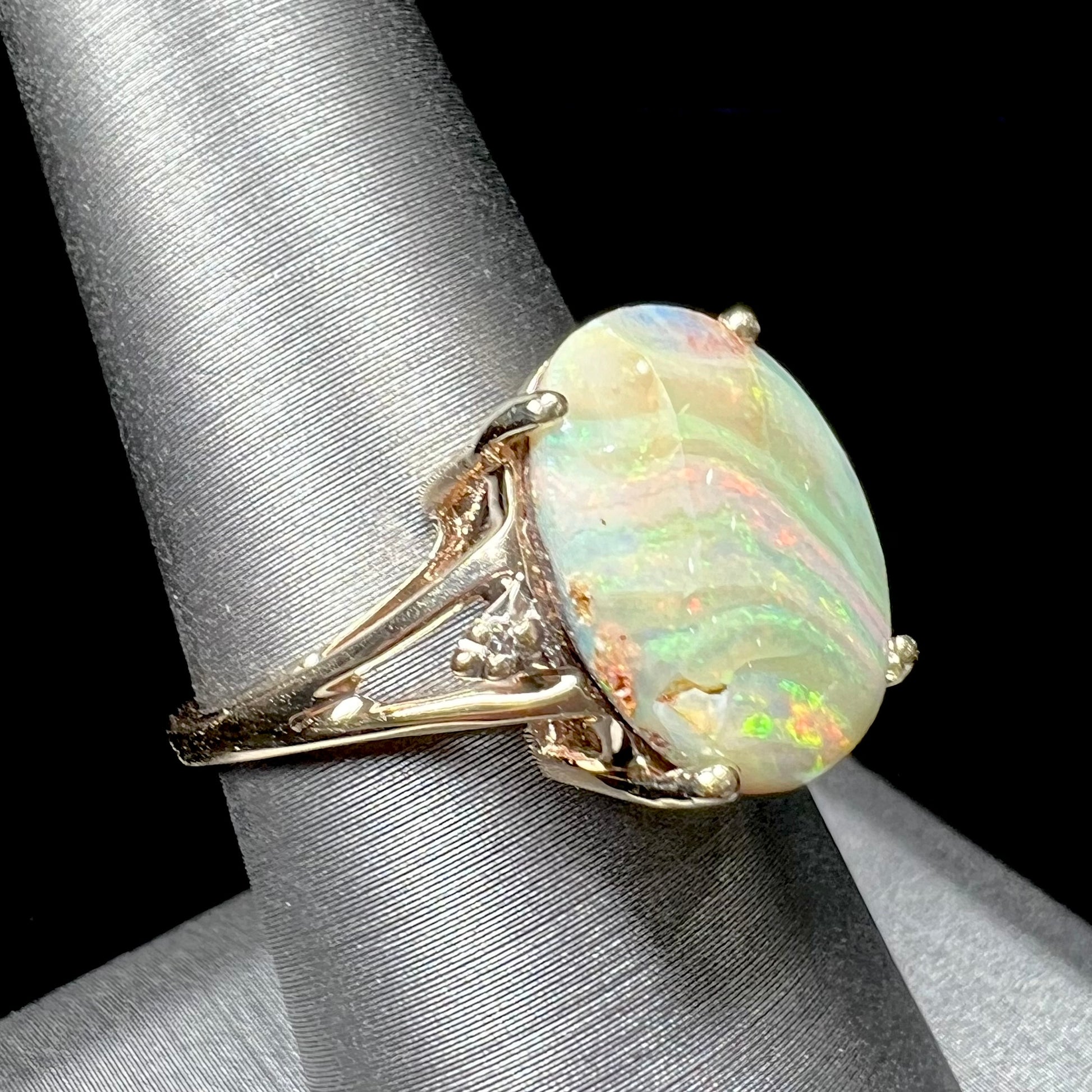 A ladies' Australian boulder opal ring set in yellow gold with diamond accents.  The opal shimmers green and pink and has fissure inclusions.