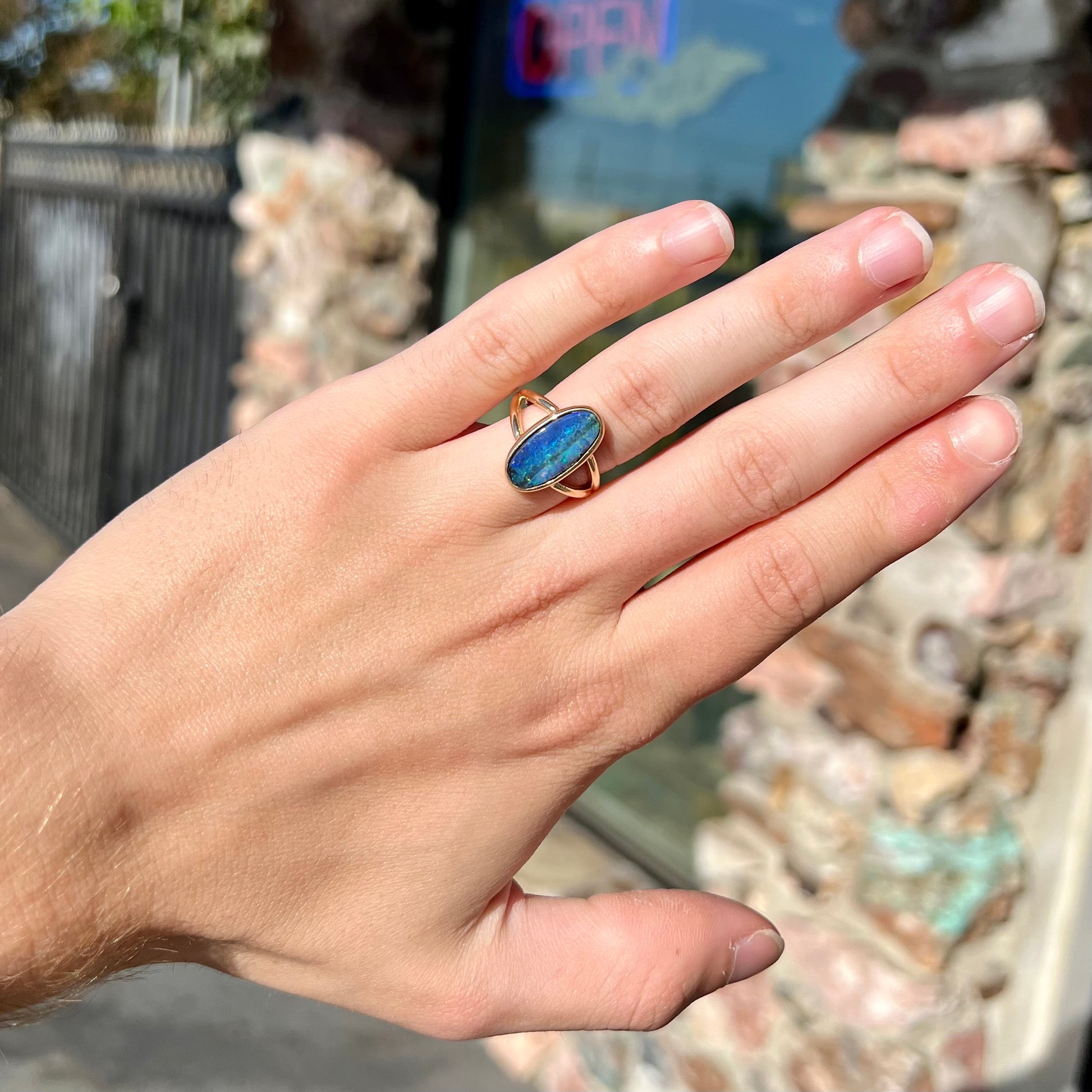 A ladies' yellow gold split shank solitaire ring set with a natural Australian black boulder opal.