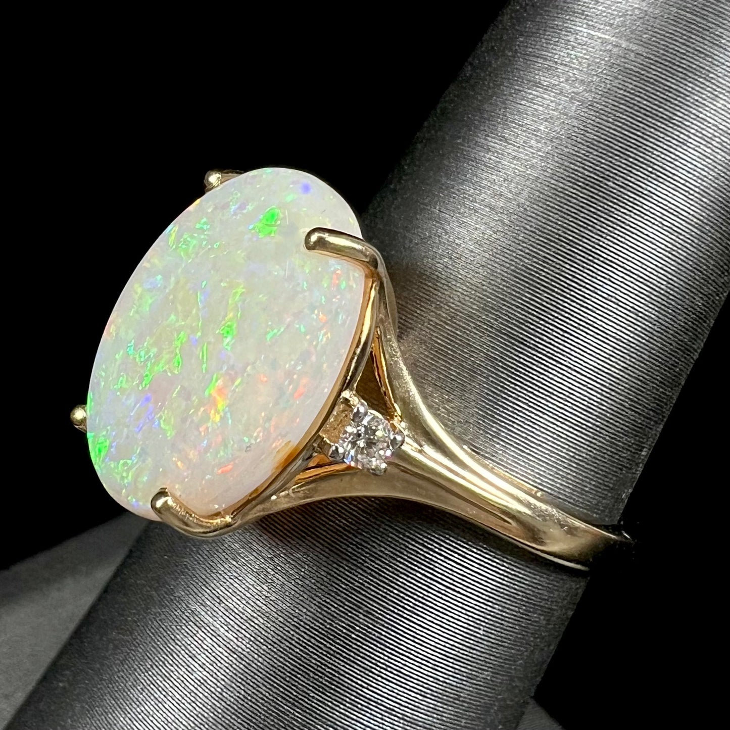 A ladies' yellow gold ring set with two diamonds and an oval cut natural opal stone.
