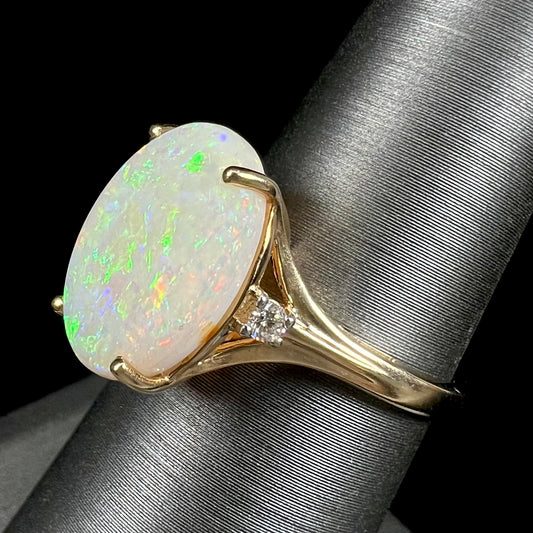 A ladies' yellow gold ring set with two diamonds and an oval cut natural opal stone.