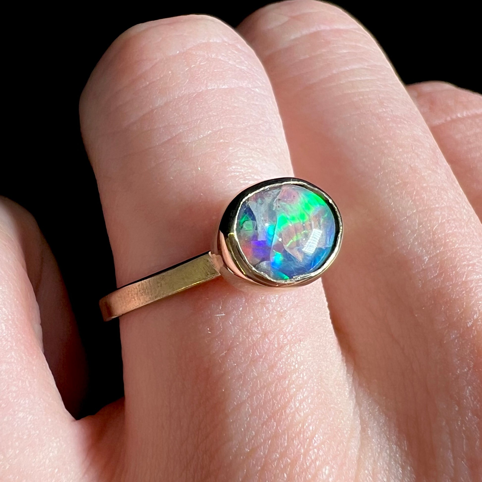 A yellow gold solitaire ring set with a natural Australian cat's eye opal stone.