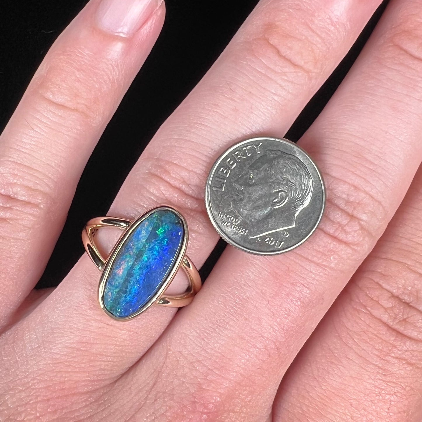 A ladies' yellow gold split shank solitaire ring set with a natural Australian black boulder opal.