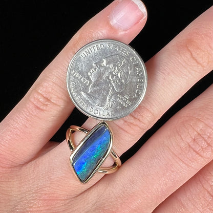 A ladies' split shank gold ring bezel set with a natural, Australian black boulder opal.