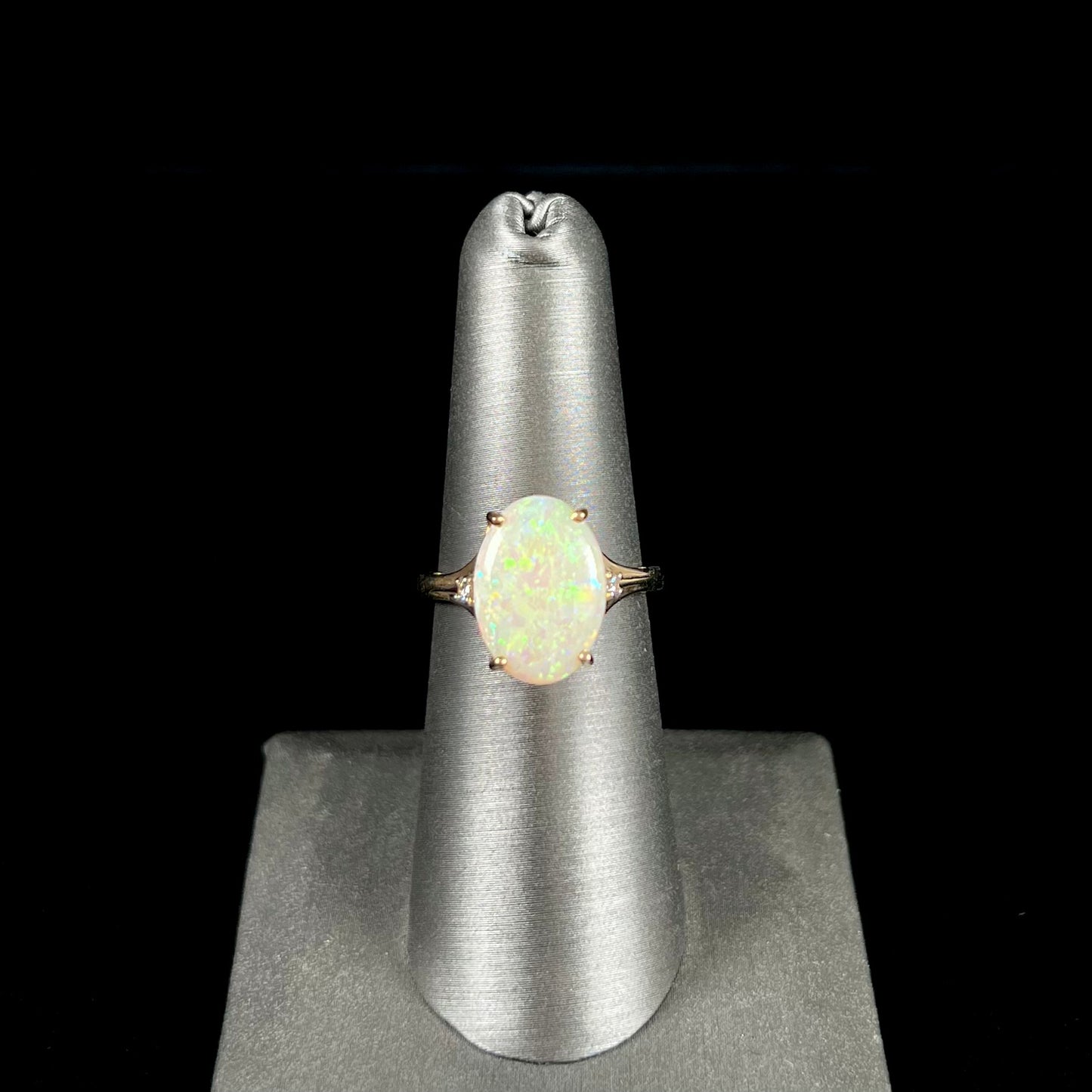 A ladies' yellow gold ring set with two diamonds and an oval cut natural opal stone.