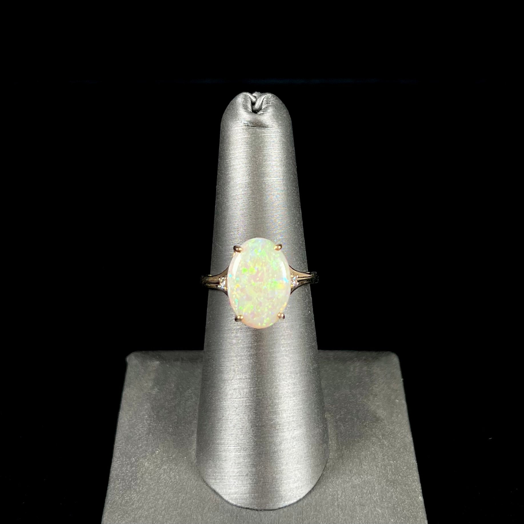 A ladies' yellow gold ring set with two diamonds and an oval cut natural opal stone.