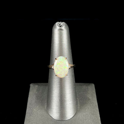 A ladies' yellow gold ring set with two diamonds and an oval cut natural opal stone.