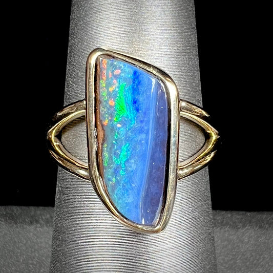 A ladies' split shank gold ring bezel set with a natural, Australian black boulder opal.