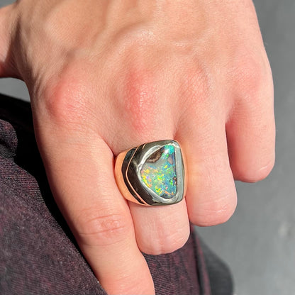 A men's yellow gold solitaire ring set with a triangular shaped natural boulder opal.