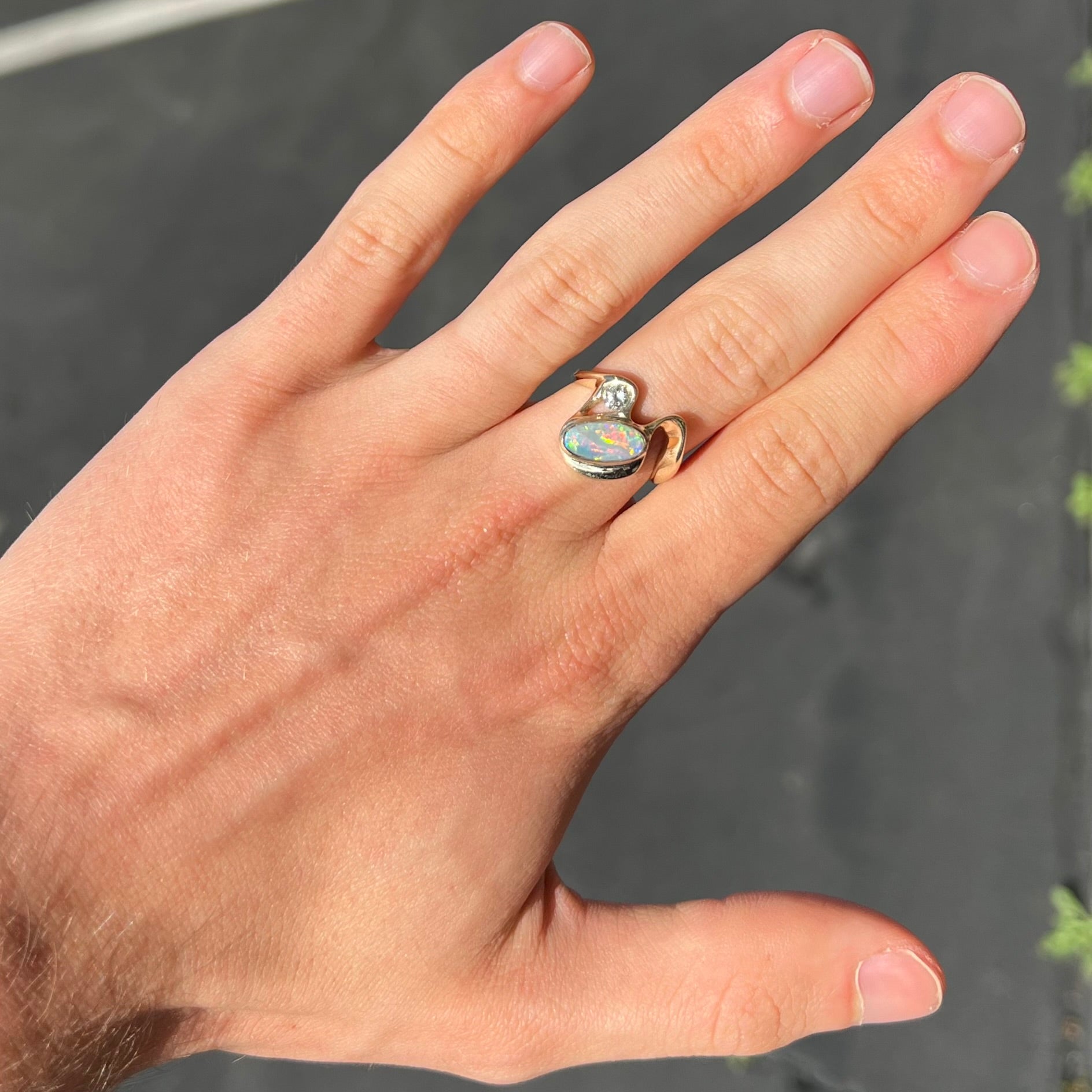 A ladies' yellow gold, bezel set ring mounted with a natural 1.15 carat black opal and round diamond.