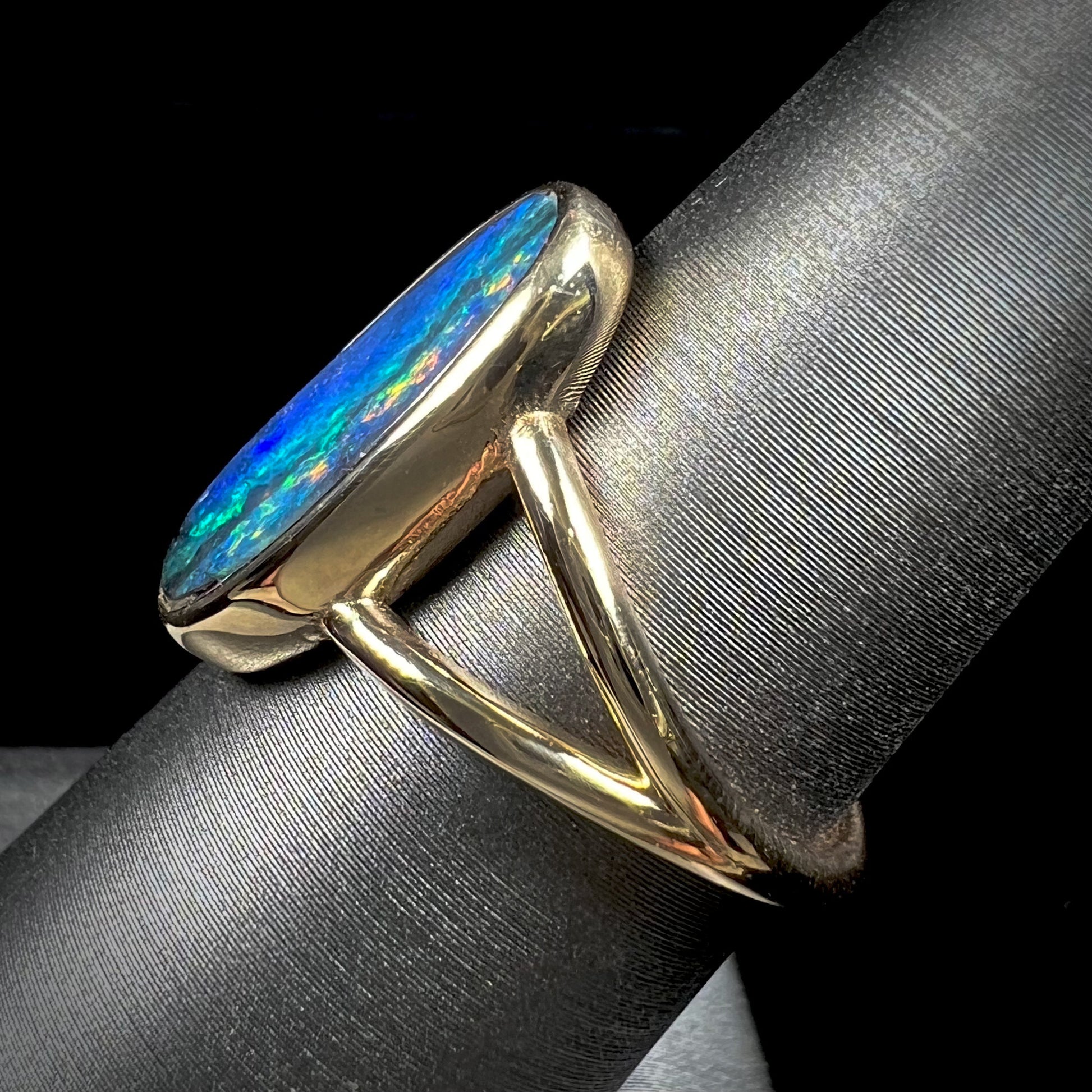 A ladies' yellow gold split shank solitaire ring set with a natural Australian black boulder opal.