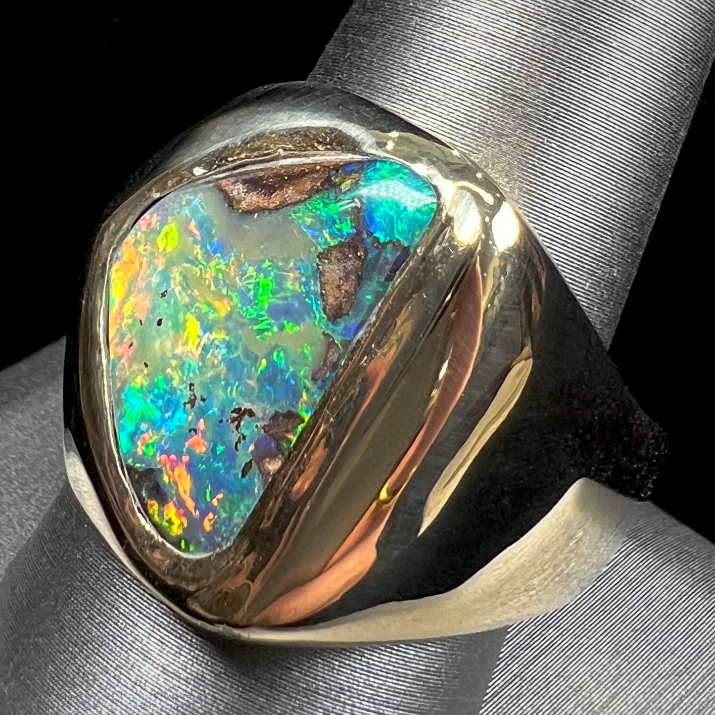 A men's yellow gold solitaire ring set with a triangular shaped natural boulder opal.