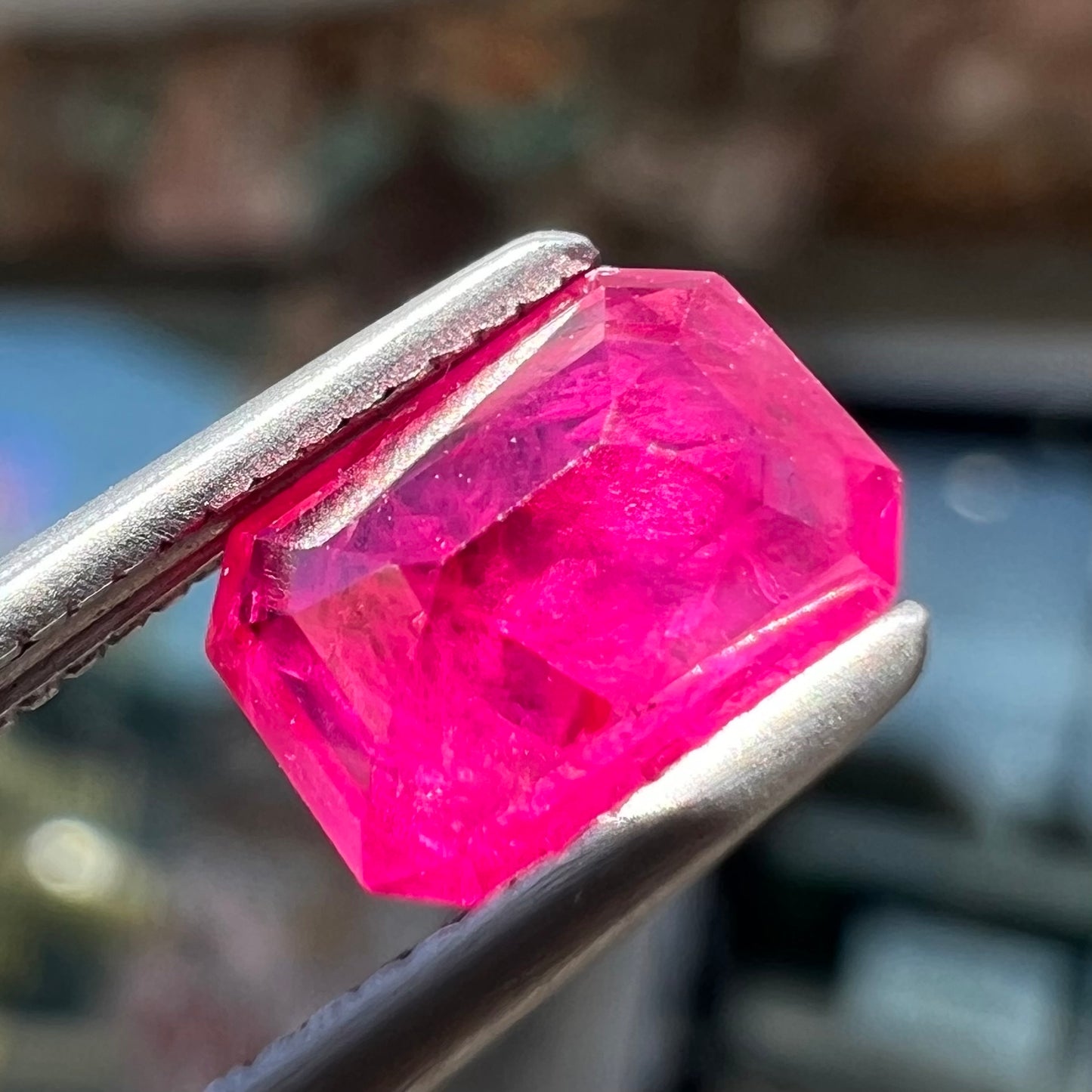 An emerald cut Burma ruby gemstone.  The stone is loose and a pinkish red color.