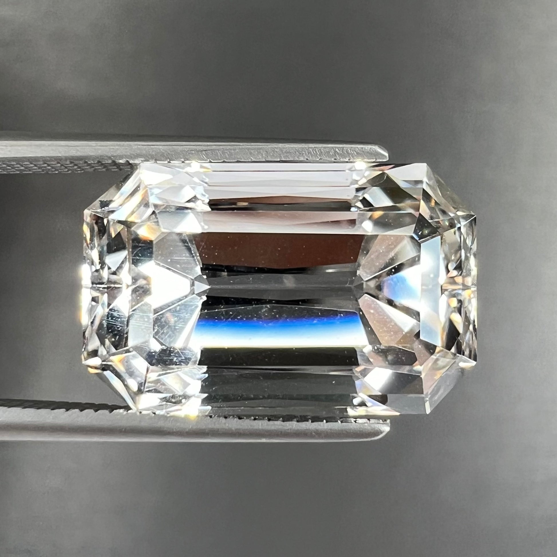 A loose, emerald cut topaz gemstone from Russia.  The stone is a faint pinkish white color.
